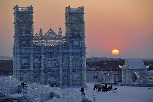 Cathedral of ice at Harbin International Ice and Snow Festival with wintry sunset in background.